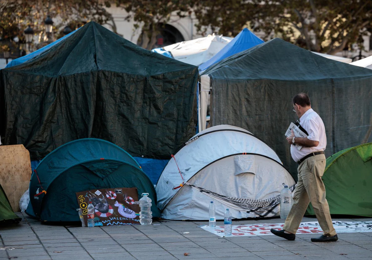 Un hombre pasa junto a la acampada por la vivienda en Valencia