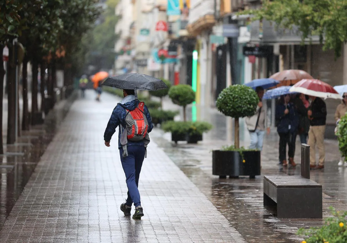 Un hombre se protege de la lluvia en el Centro