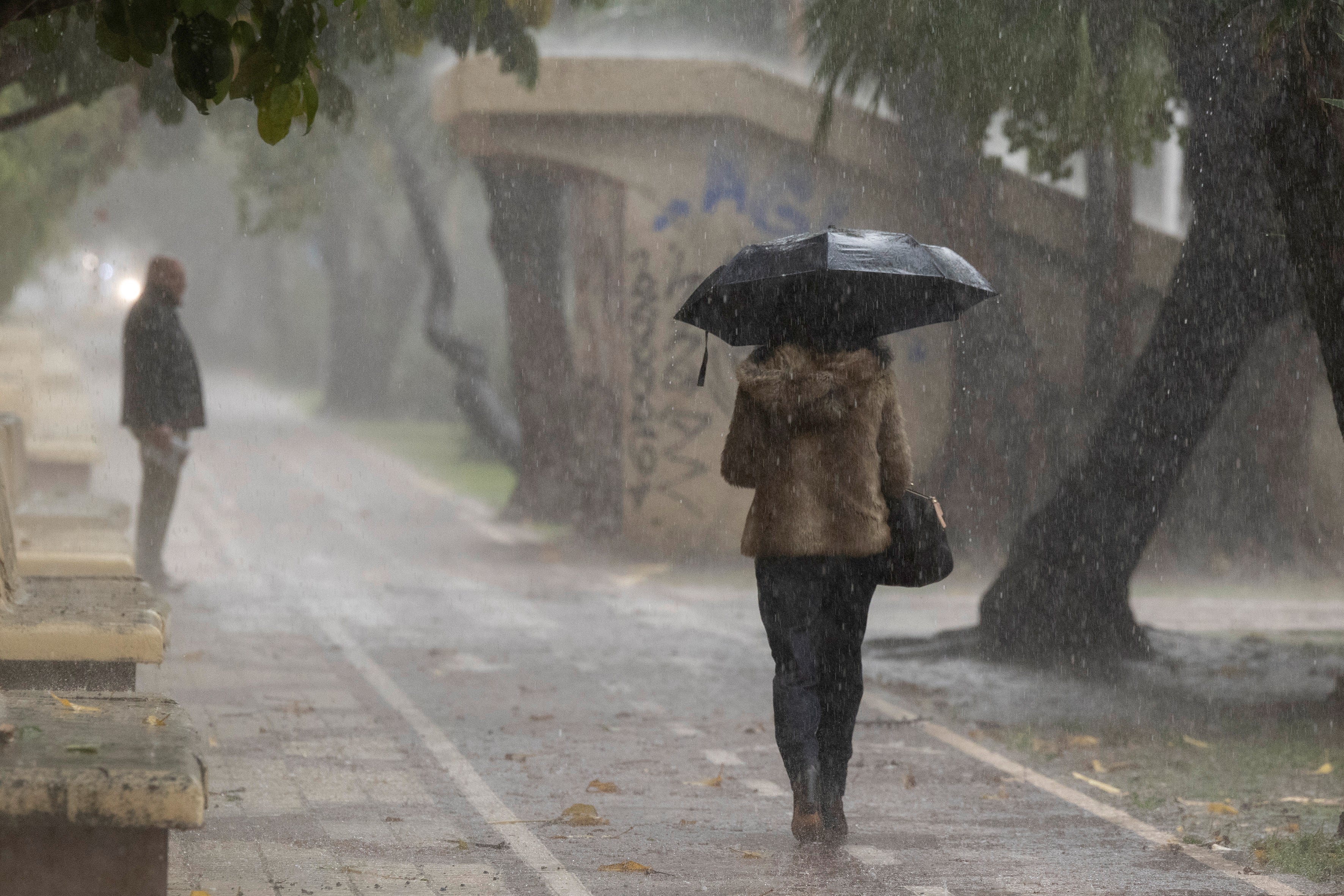 Una mujer se resguarda de la lluvia en Málaga