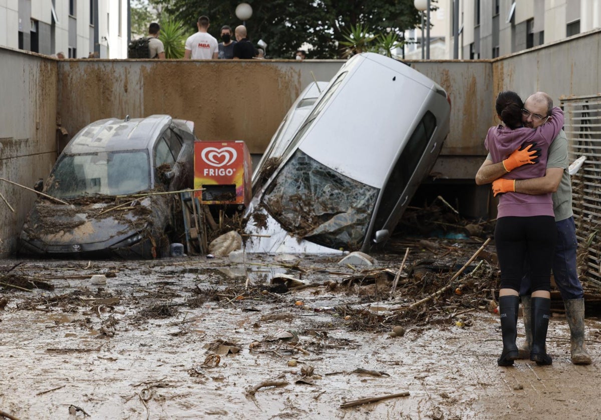 Dos vecinos se abrazan a la entrada de un garaje en Paiporta (Valencia)