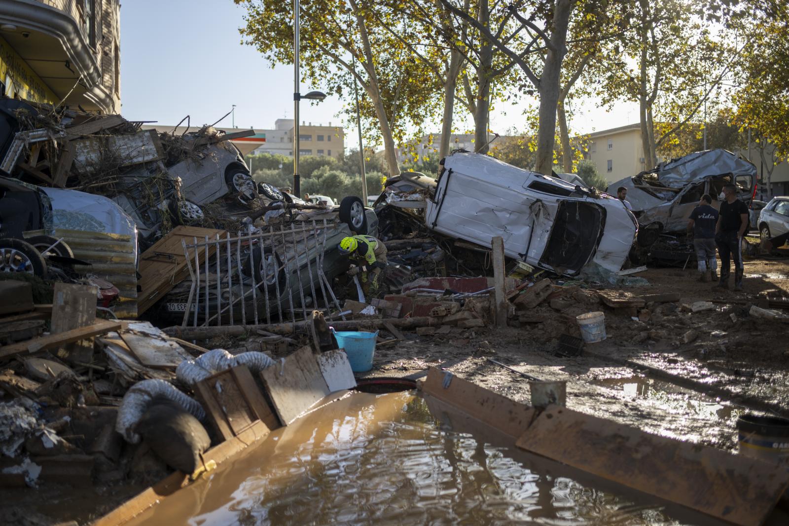 Varios bomberos buscan a personas entre coches en Alfafar, Valencia