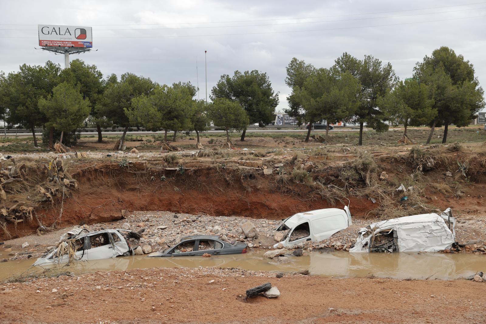 Coches destrozados y semienterrados por el paso de la dana en un barranco próximo al Centro Comercial Bonaire, en Valencia, este domingo. EFE/Manuel Bruque