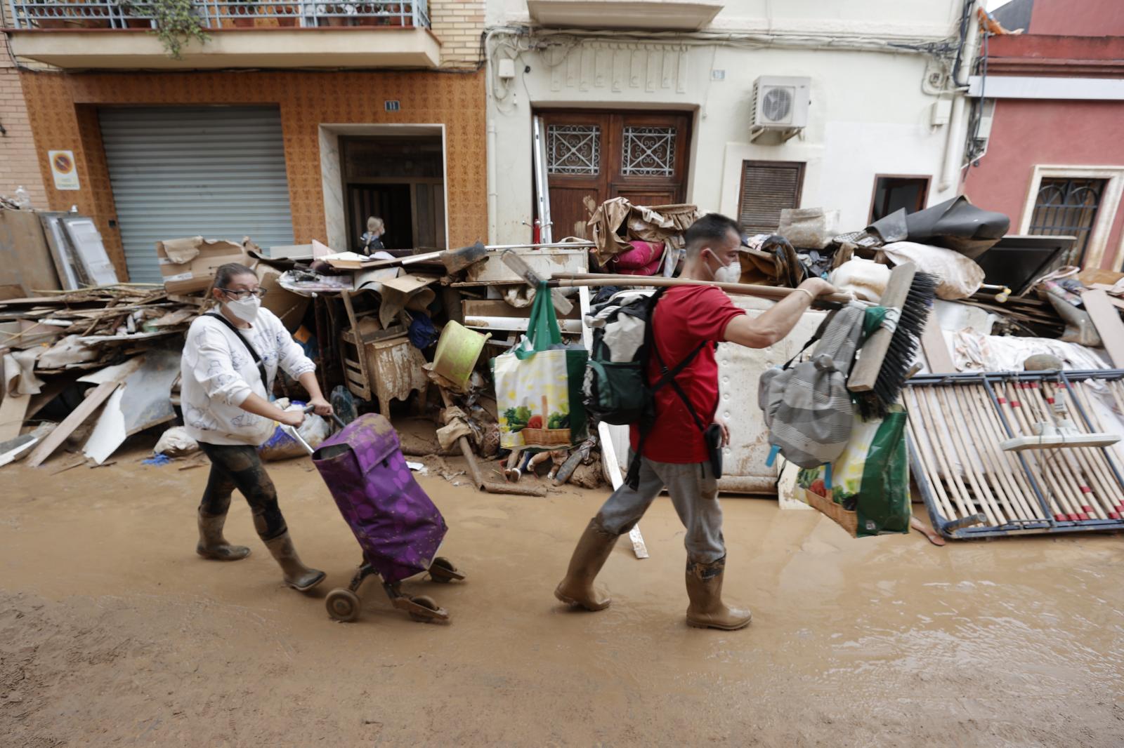 Dos personas cargan con sus pertenencias por las calles de Paiporta, Valencia