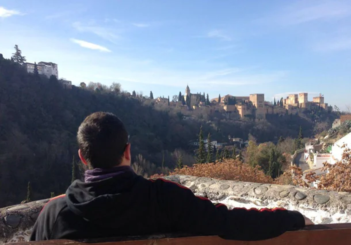 Un viajero descansa en un banco del Sacromonte mirando a la Alhambra tras (casi) completar la ruta