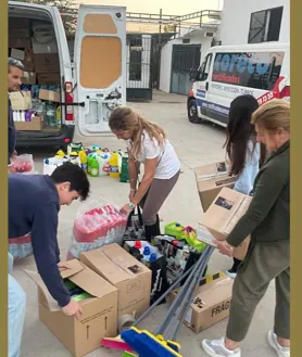 Imagen secundaria 2 - En la imagen superior, coches amontonados en una calle de Guadassuar. Debajo a la derecha, material enviado por la hermandad del Vía Crucis. A la izquierda, cofrades de Pasión organizando la ropa y demás productos que enviarán pronto  