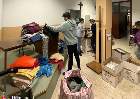 Imagen secundaria 1 - En la imagen superior, coches amontonados en una calle de Guadassuar. Debajo a la derecha, material enviado por la hermandad del Vía Crucis. A la izquierda, cofrades de Pasión organizando la ropa y demás productos que enviarán pronto  