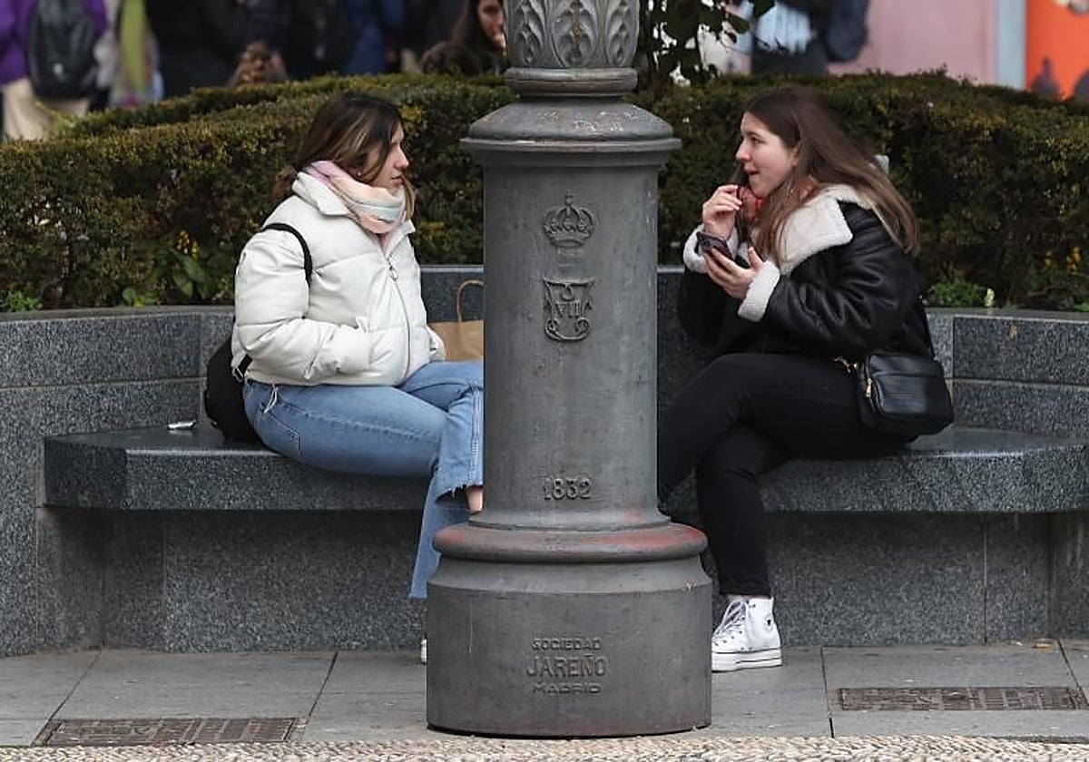 Dos jóvenes en un banco de las Tendillas conversando abrigadas