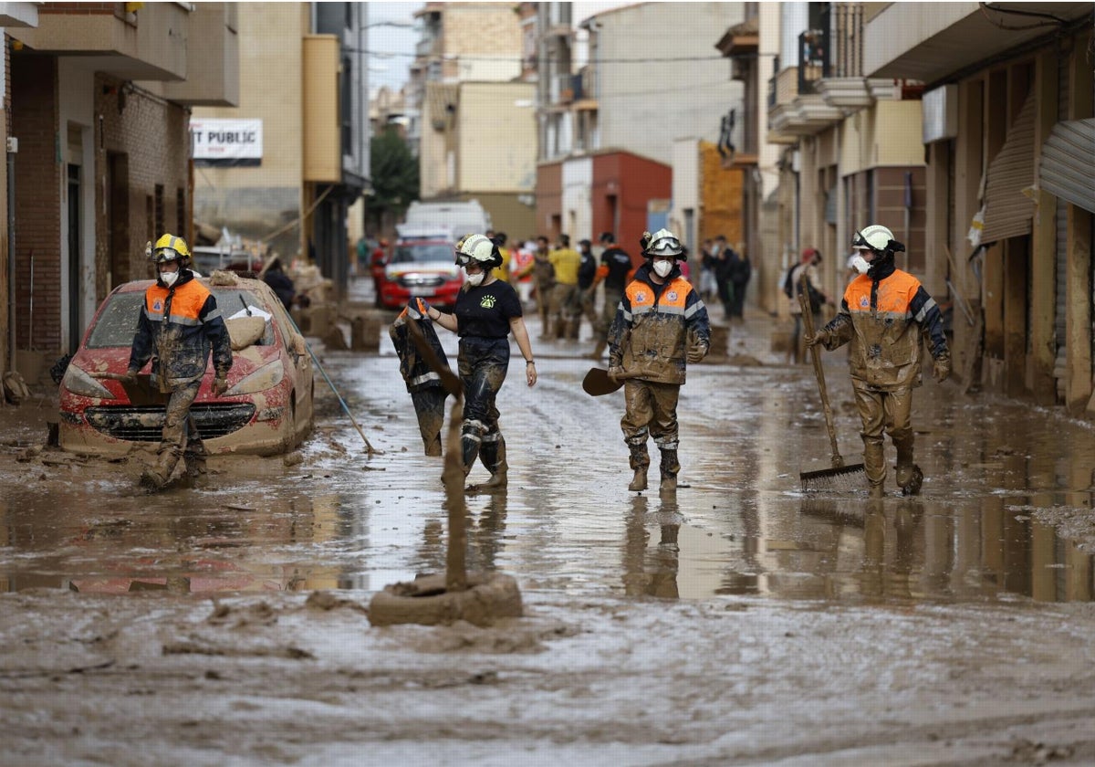 Bomberos trabajan en la limpieza de una calle afectada por la riada tras la DANA