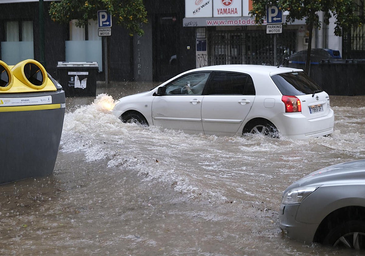 Un coche circulando por una céntrica calle de Málaga completamente anegada este miércoles