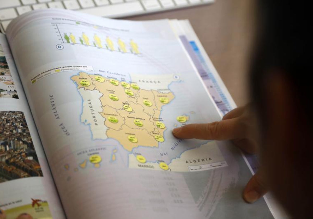 Una alumna revisa un mapa de España en valenciano, en un libro escolar