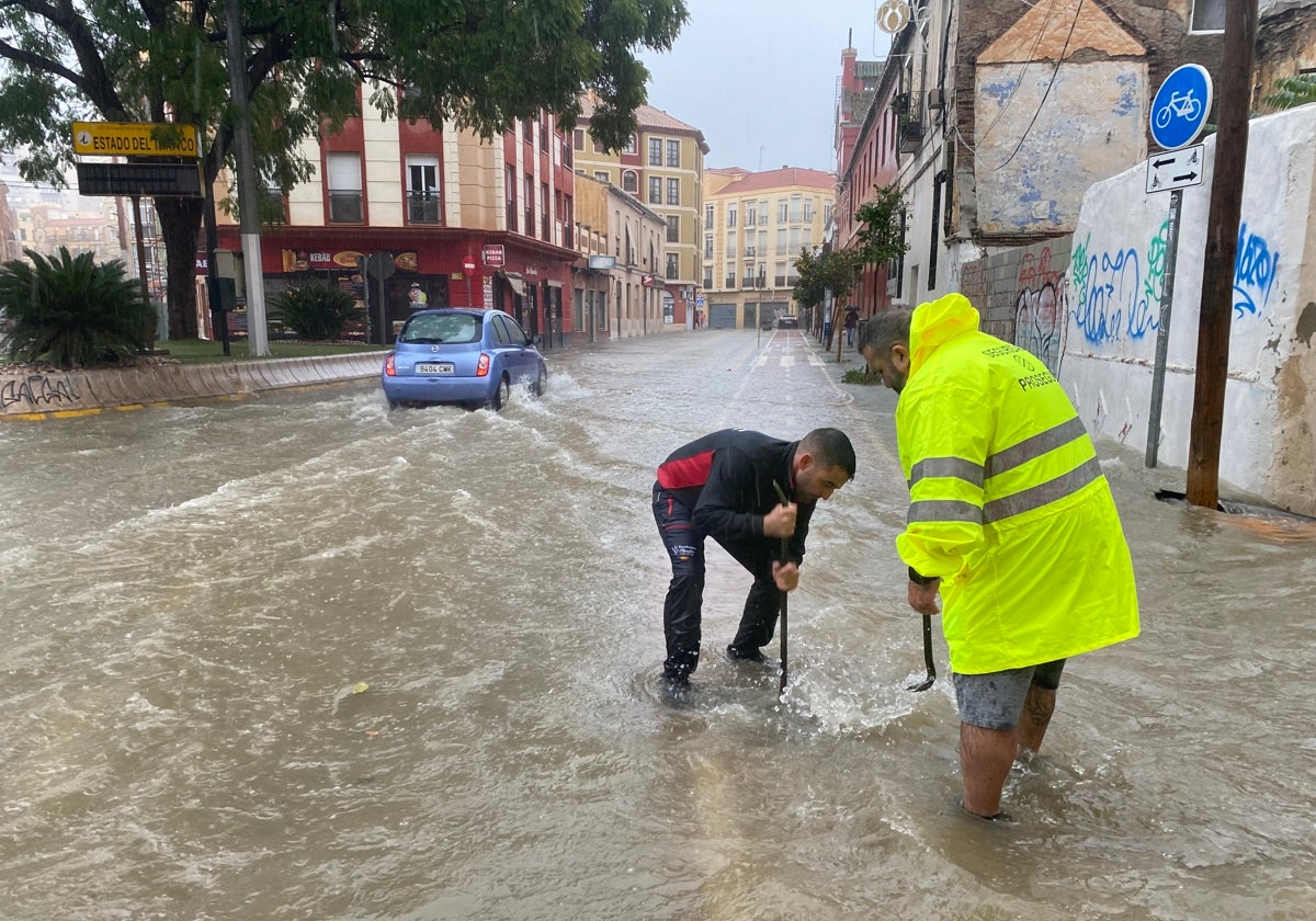 Operarios abren las alcantarillas para descargar el agua que se concentraba en las calles del centro de Málaga