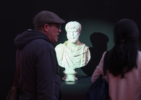 Imagen secundaria 1 - Arriba, teatralización 'Con los ojos del poeta'. Debajo, el busto romano de Quintana del Marco y uno de los actores de la feria interactuando con algunos visitantes