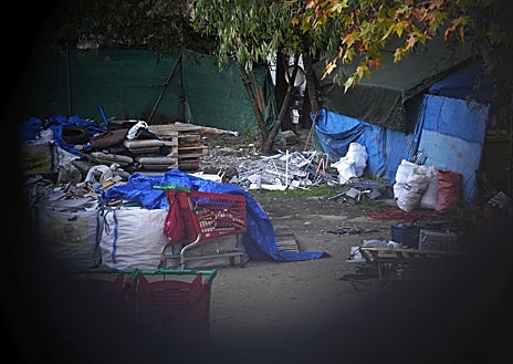 Imagen secundaria 1 - Arriba, el pabellón con una tela de protección desde que se paralizó su derrumbe. Abajo, izq, restos de basura de los asentados en el solar. Dcha, el candado instalado