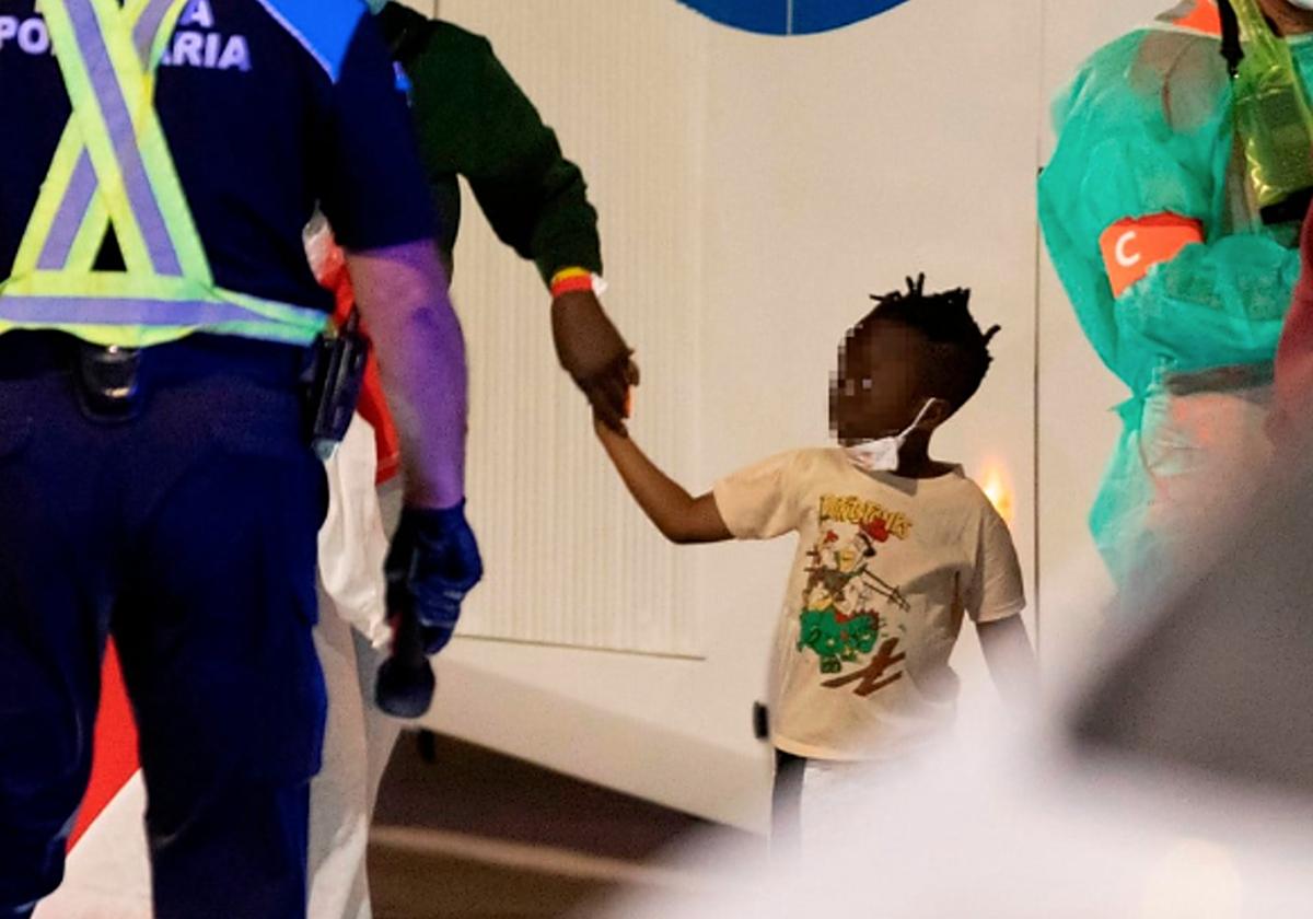 Una niña rescatada de un cayuco en Canarias, junto a los equipos de rescate y asistencia en el muelle