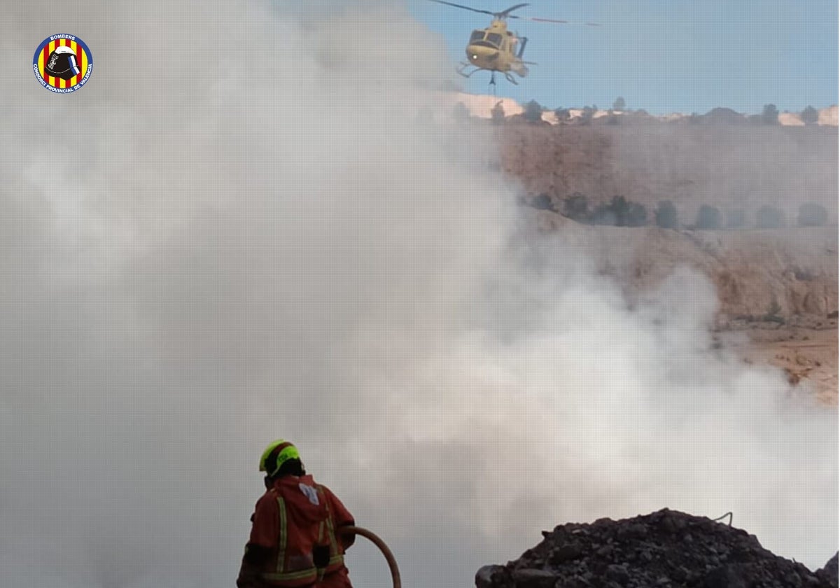 Bomberos trabajan con apoyo de un helicóptero en la extinción del incendio en Alberic (Valencia)