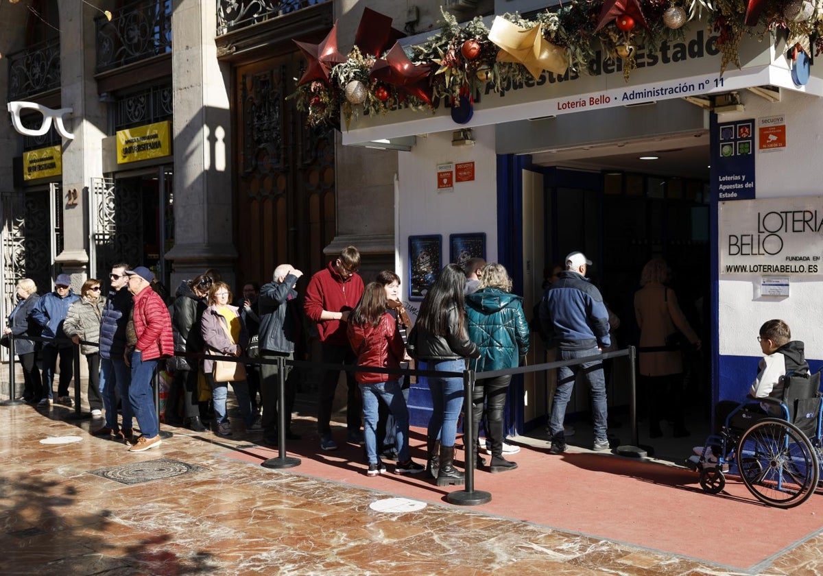 Varias personas hacen cola en una administración de lotería del centro de Valencia