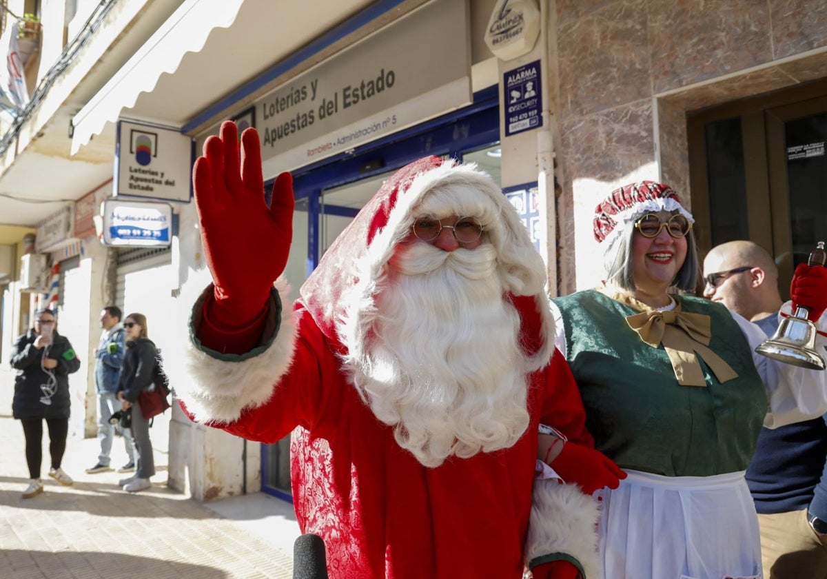 Una persona disfrazada de Papá Noel saluda ante la administración número 5 de Catarroja (Valencia)