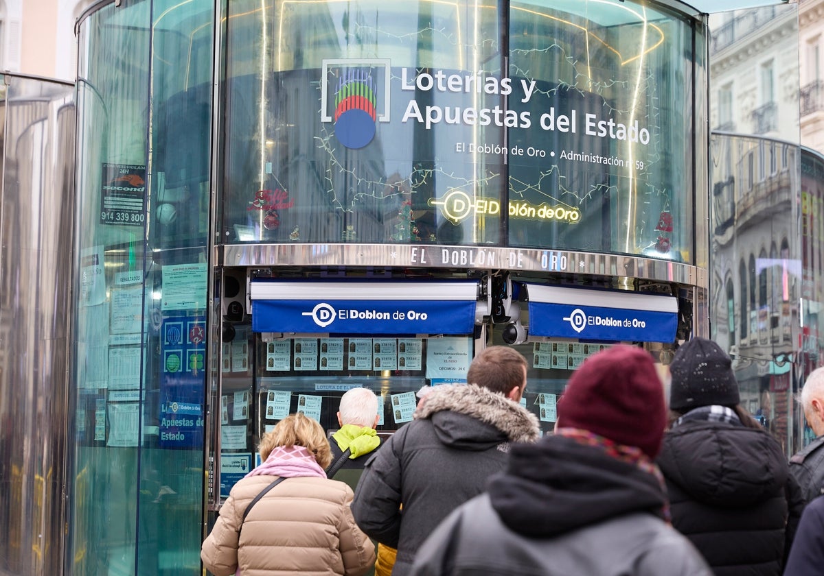 Varias personas hacen cola para comprar lotería para el Sorteo Extraordinario de Navidad en una administración de Madrid, 'El Doblón de Oro'