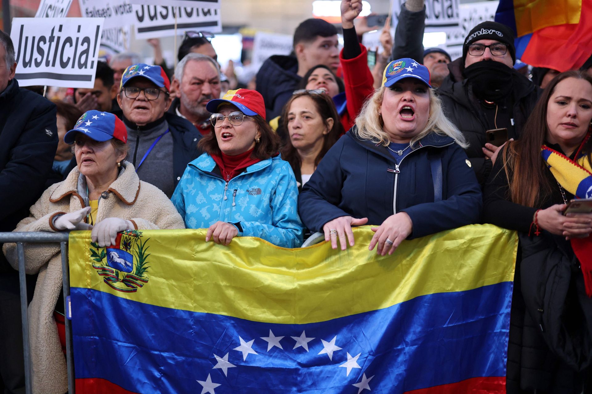 Asistentes a la concentración en Madrid sostienen una bandera de Venezuela.