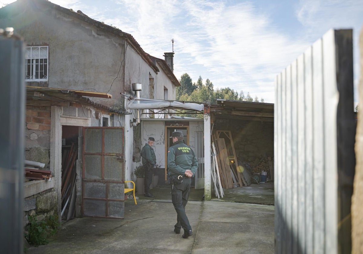 Dos guardias civiles inspeccionan la vivienda asaltada, situada en una zona aislada del municipio de Meis