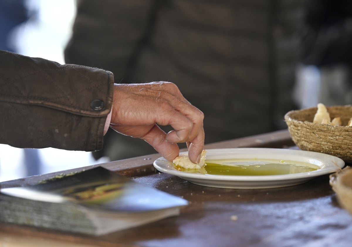 Un visitante moja pan en uno de los stand donde se hacen catas de los aceites de oliva virgen extra