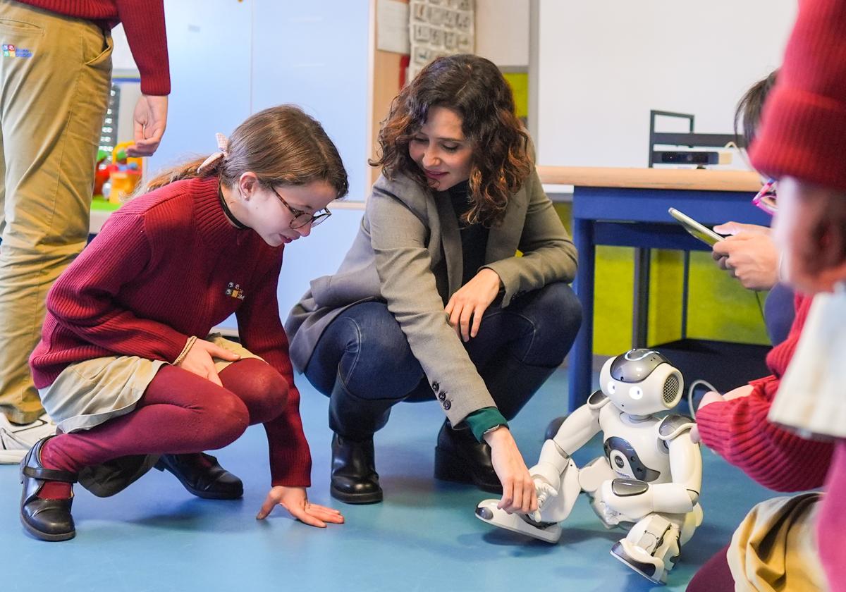 La presidenta de la Comunidad, Díaz Ayuso, junto a niños y Robic en una visita al colegio Gaudem de Madrid, este lunes