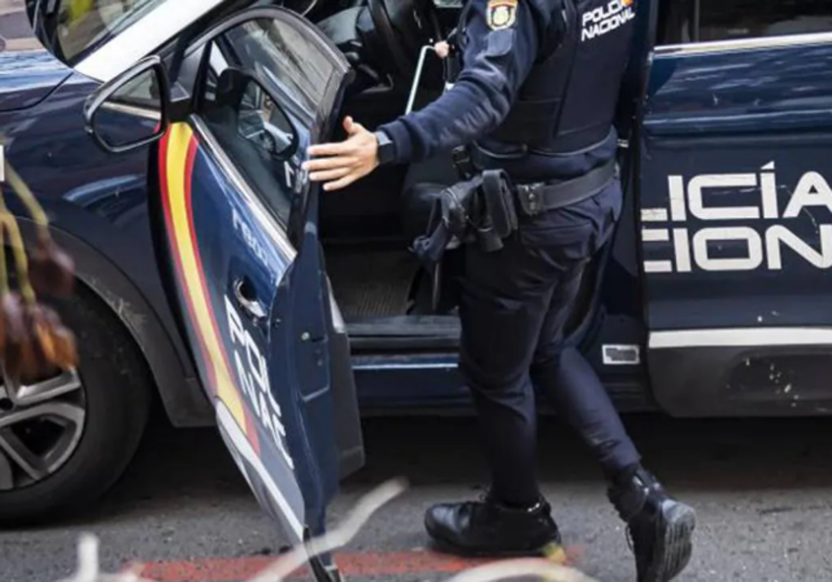 Un agente de la Policía Nacional subiendo a un coche patrulla.