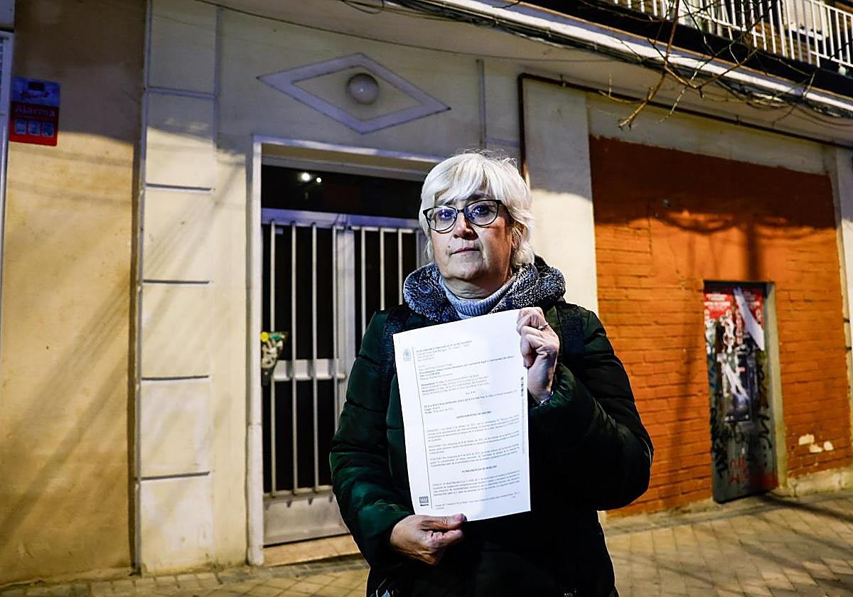 Nuria posa frente a su piso okupada y con el auto que suspendía el primer desahucio