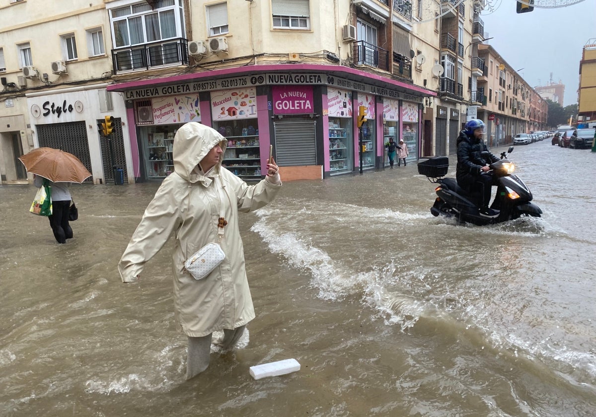 Imagen de una mujer en una calle inundada de Málaga durante la dana de noviembre