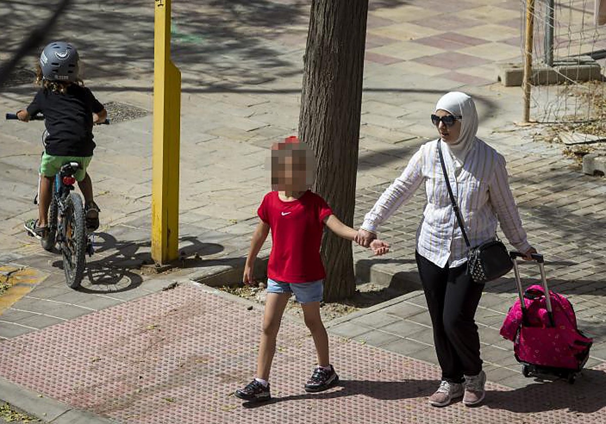 Una mujer lleva a una niña al colegio en Alicante