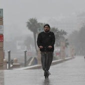 Un hombre en patinete bajo la lluvia