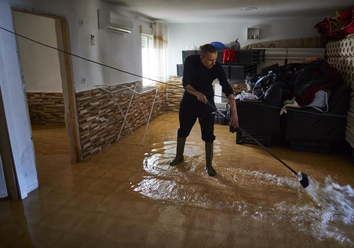 Anwar achica el agua de su casa en Las Sabinas, inundaba al crecer el río Guadarrama