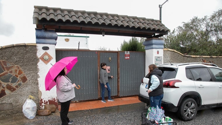 Tres mujeres conversan en la puerta de una casa