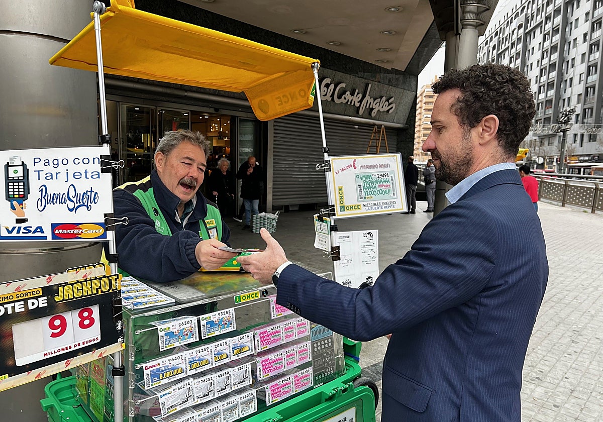 El vendedor de la ONCE Vicente Barberá, con un cliente en su puesto en Valencia