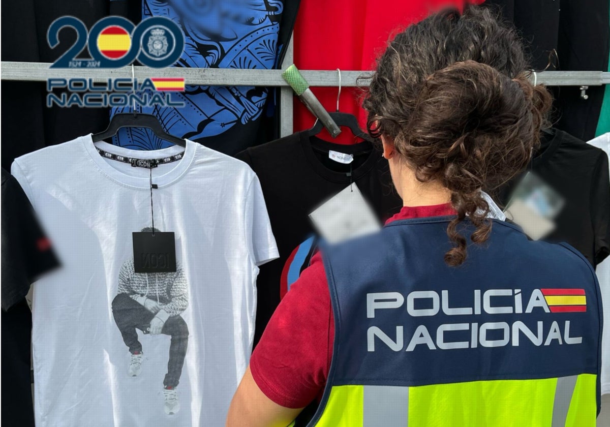 Una agente de la Policía Nacional revisa prendas falsificadas en uno de los puestos de venta en el mercadillo de Benidorm