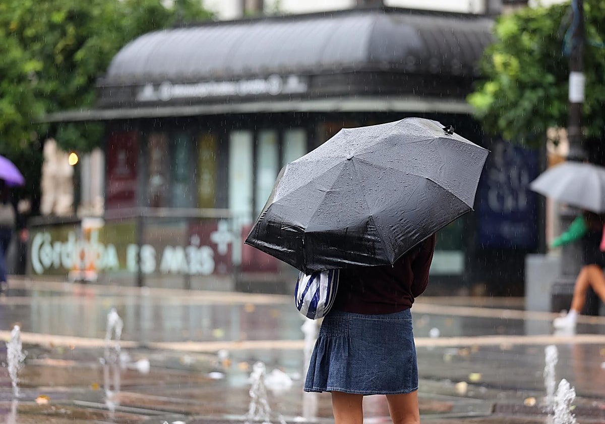 Una mujer se protege de la lluvia en Córdoba durante las borrascas vividas en marzo