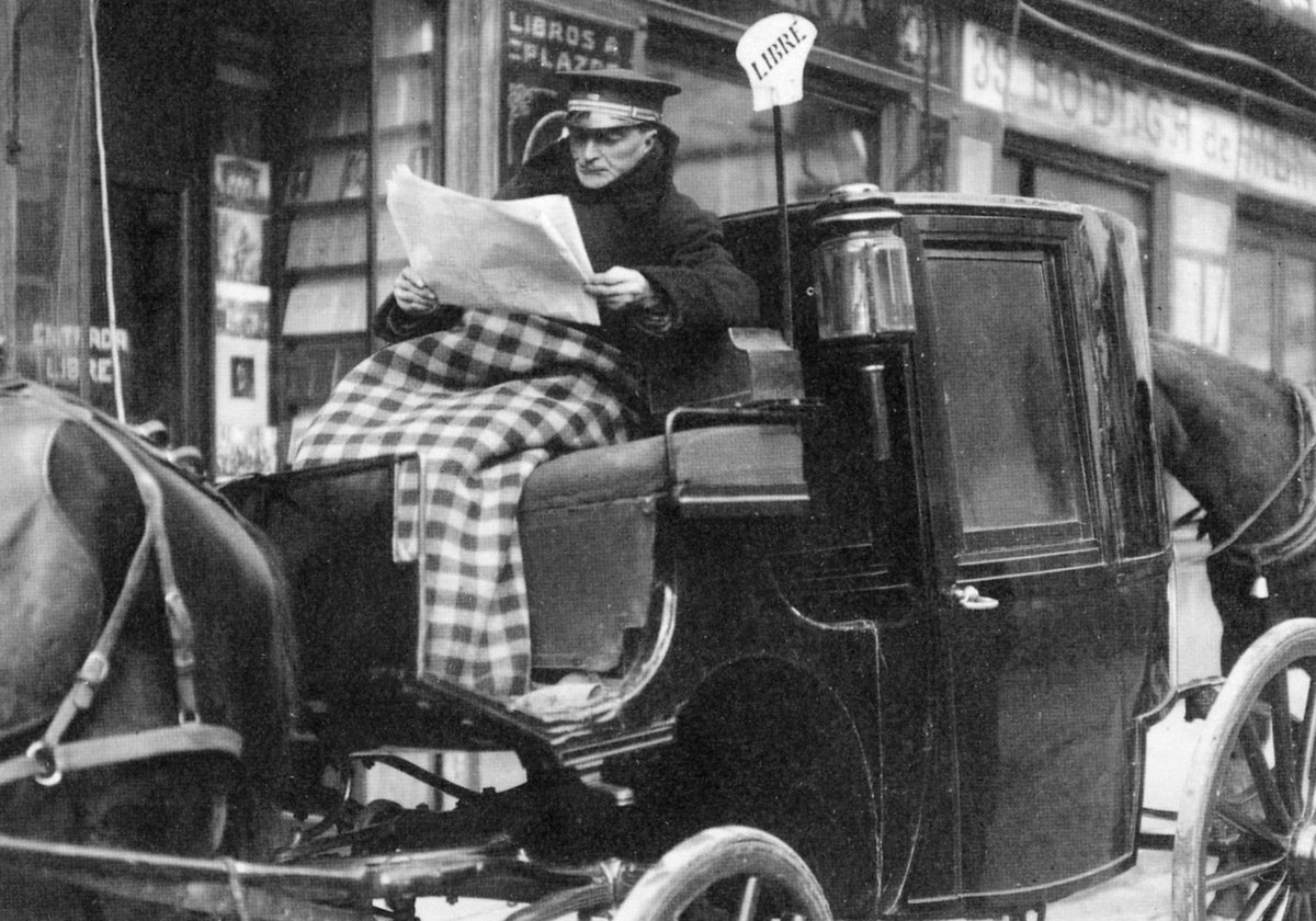 Un cochero libre aguarda, leyendo el periódico, la llegada de clientes. Madrid, 1920
