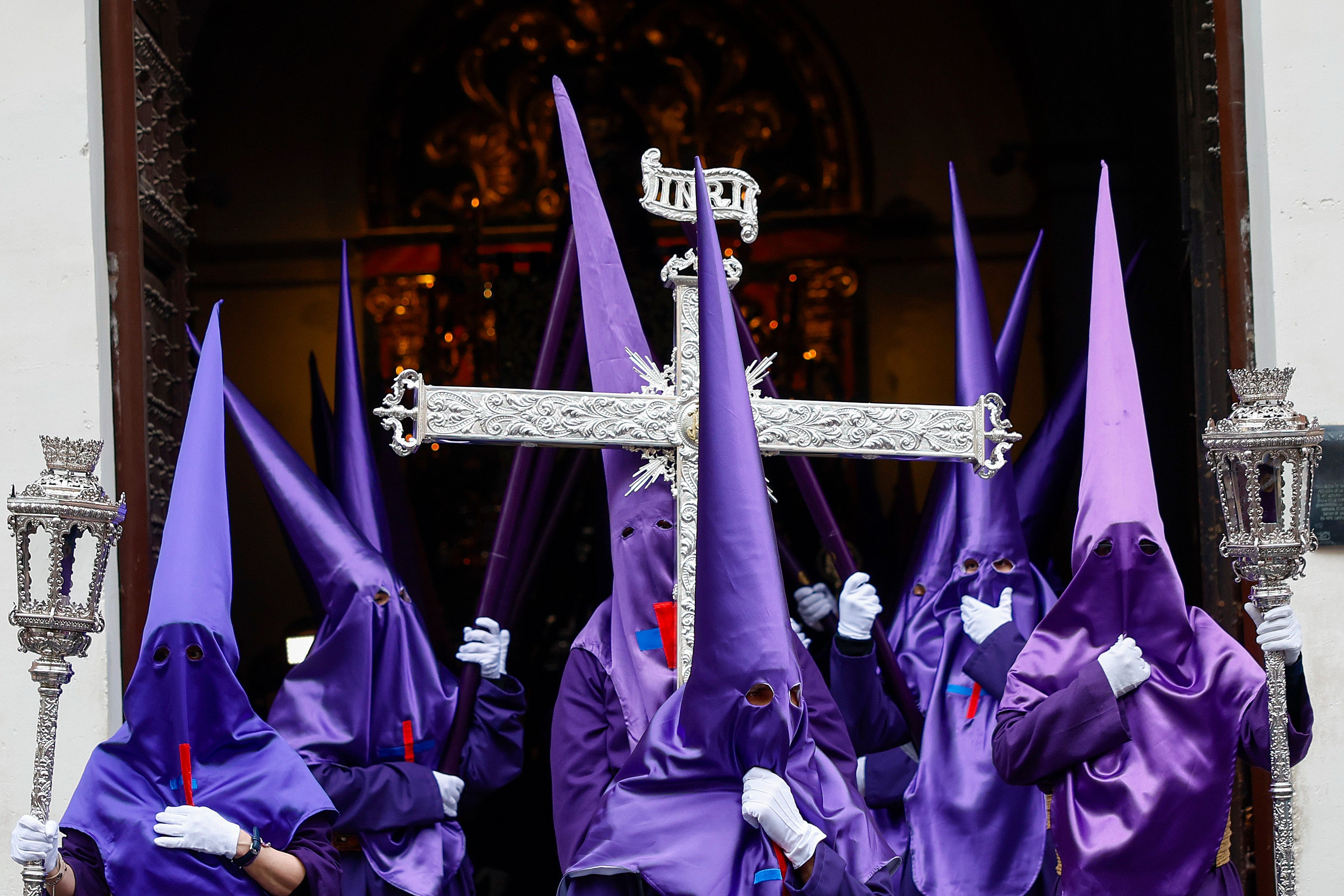 Nazarenos portan a la salida de la Iglesia el estandarte de la Santa Cruz antes de comenzar la procesión en Madrid