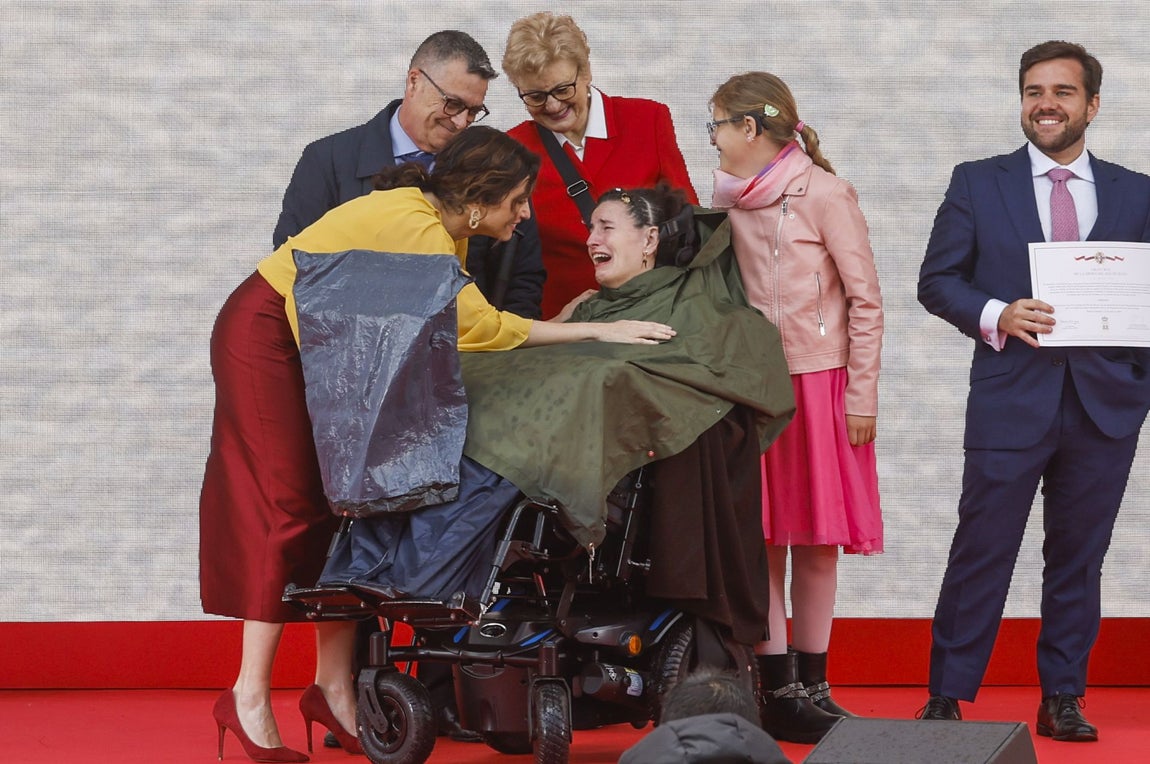 La presidenta de la Comunidad de Madrid, Isabel Díaz Ayuso, junto a profesionales y pacientes del centro de atención diurna para ELA del Isabel Zendal, durante el acto institucional de entrega de las Grandes Cruces de la Orden del Dos de Mayo.