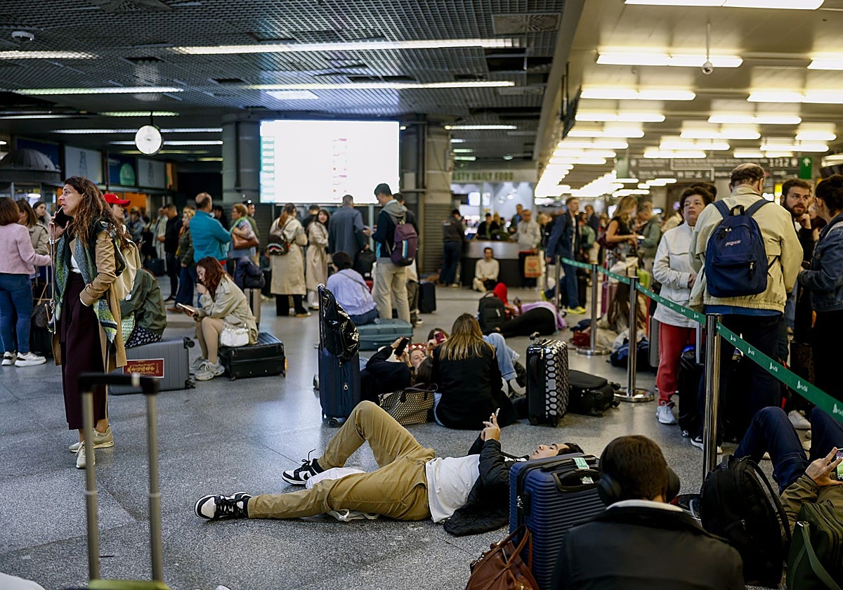 Varios viajeros aguardan en la estación de Atocha tras la demora de sus trenes