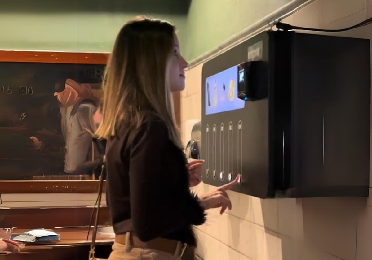 Una joven usa el original dispensador ubicado en los baños del Mae West de Granada