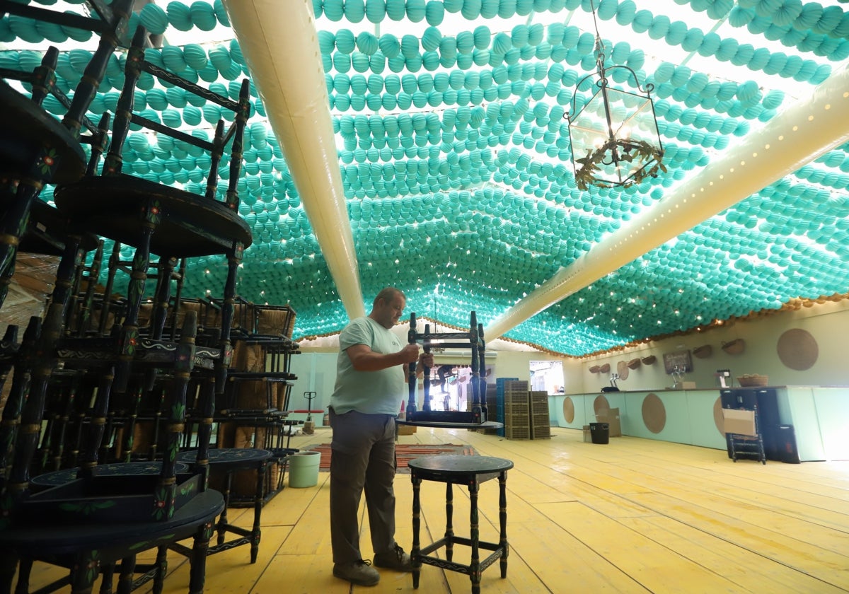 Un operario monta mesas en el interior de la caseta de la Asociación Salmorejo y Perejil