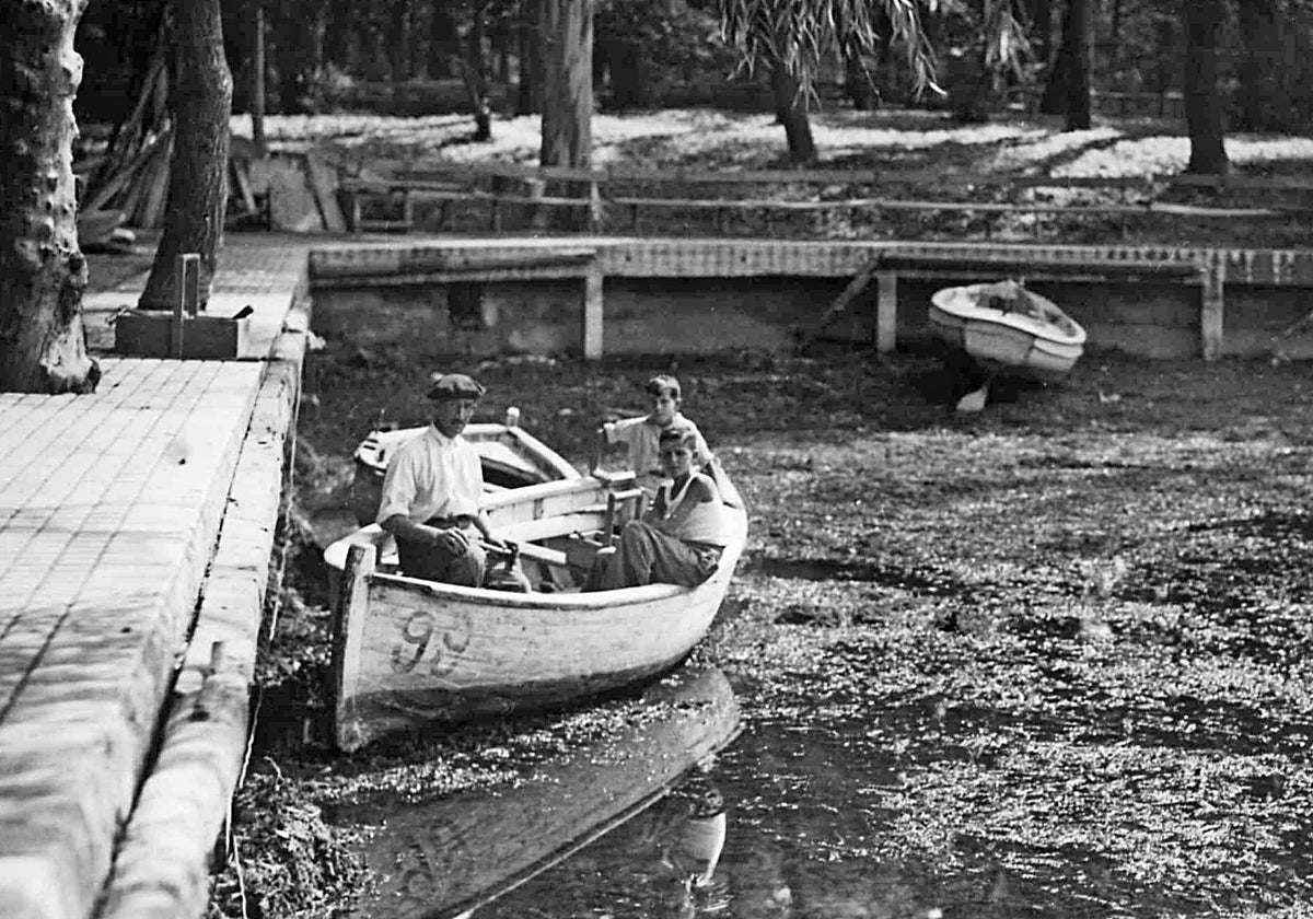 Varias personas en una barca en el estanque de El Retiro, que luce un bajísimo nivel del agua en el verano de 1935