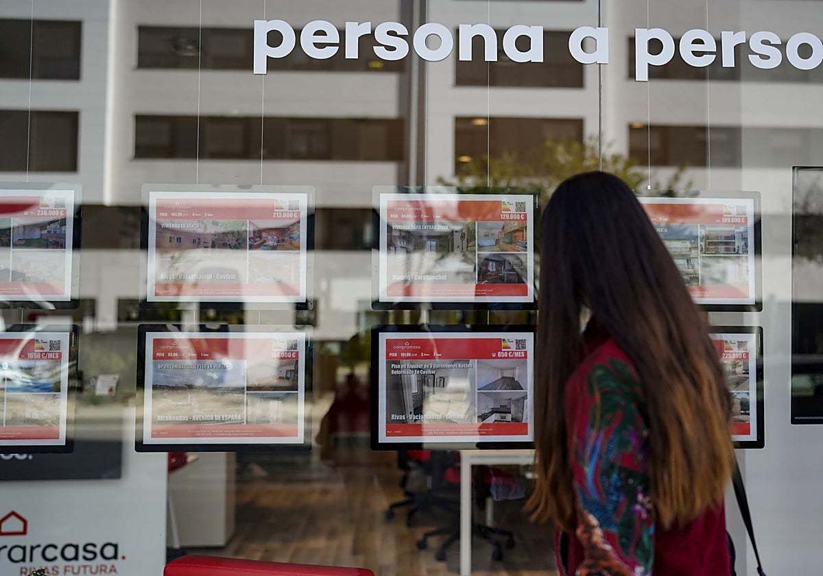 Una joven contempla el escaparate de una inmobiliaria en Madrid