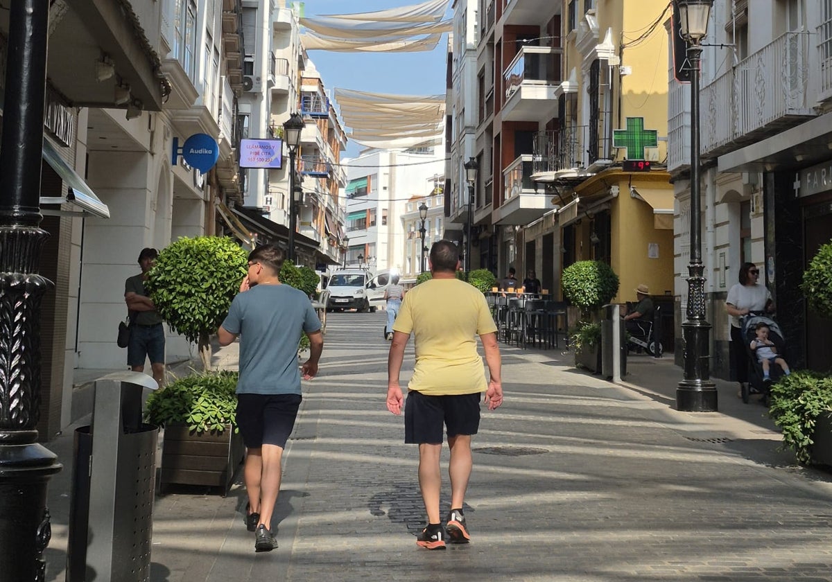 Dos viandantes cruzan la calle El Peso una de las arterias comerciales de Lucena
