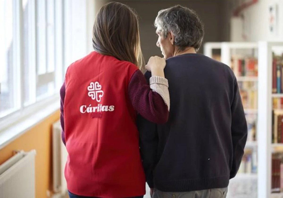 Una voluntaria de Cáritas acompañando un usuario en foto de archivo