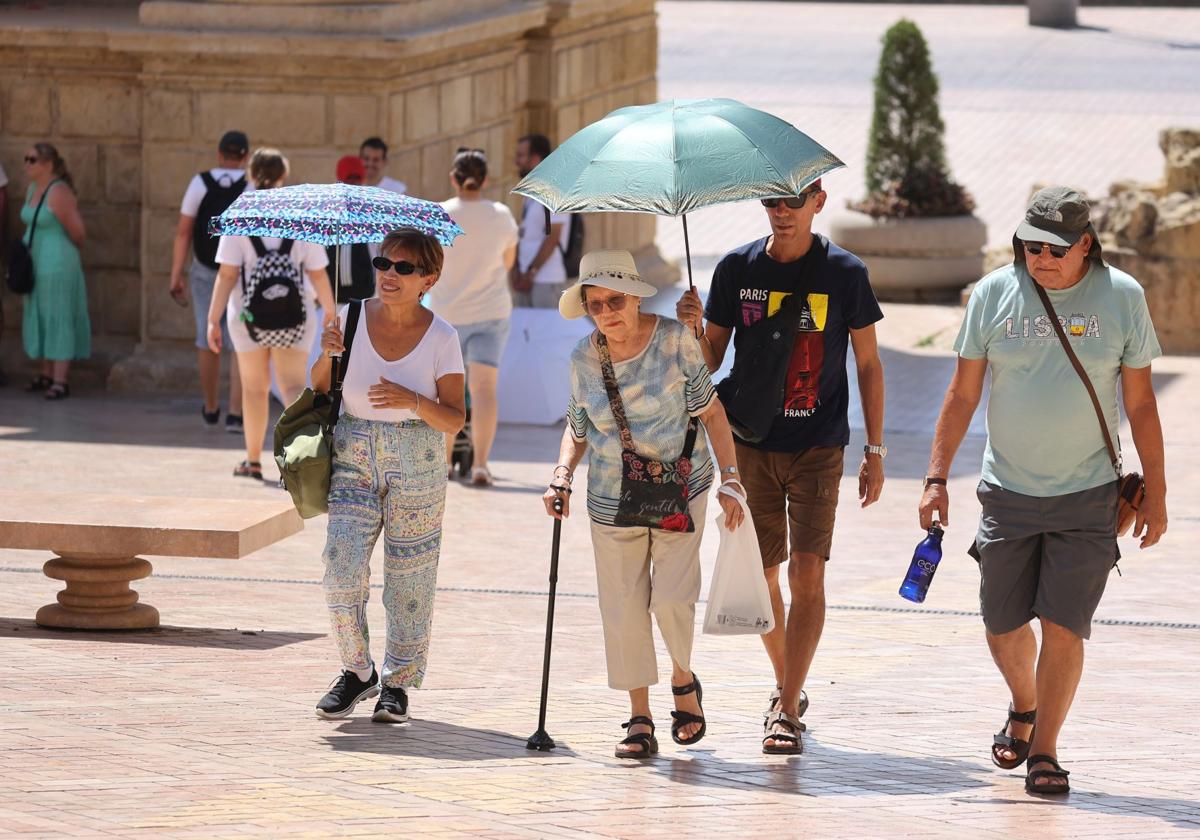 Unos turistas con paragüas para protegerse del sol en la Puerta del Puente