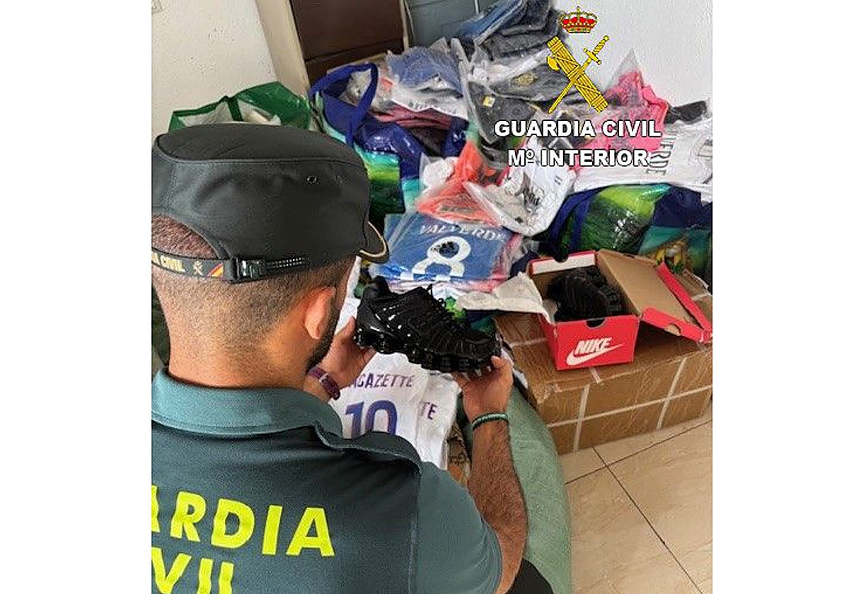 Imagen de un agente de la Guardia Civil con los productos falsificados decomisados
