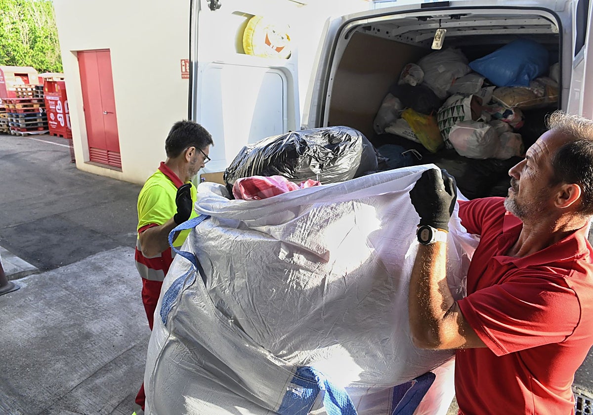 Dos operarios de Cáritas durante la recogida de la ropa usada en sus instalaciones de Solemcor
