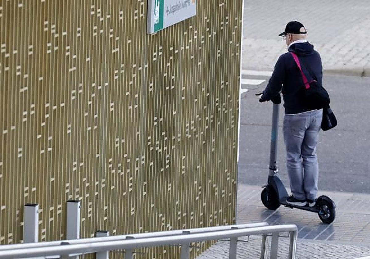 Un hombre en patinete en la acera de la Ciudad de la Justicia de Córdoba